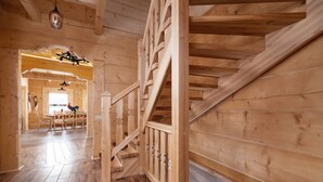 Eine Holztretreppe mit Geländer, die zu einem Essbereich mit Tisch und Stühlen führt.
