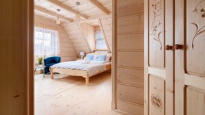 Ein Zimmer aus Holz mit einem Bett, einem Stuhl und einem Tisch.