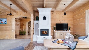 Ein gemütliches Holzhaus-Interieur mit Kamin, Fernseher und einer bequemen Sitzecke.