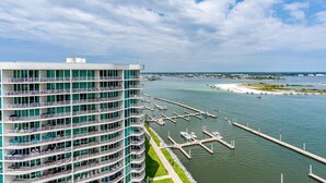 A multi-story hotel with balconies overlooking a marina and a beach.