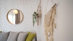 Ein Zimmer mit einem runden Spiegel, einer Wanddekoration aus Makramee und einer Makramee-Pendelleuchte.