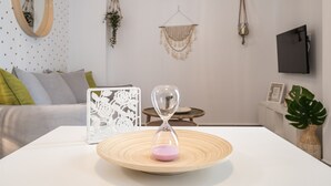 Ein modernes Wohnzimmer mit einem weißen Sofa, einer dekorativen Sanduhr und einem weißen Tisch.
