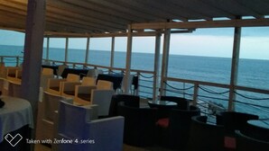 Un espace extérieur aménagé avec des tables et des chaises, offrant une vue sur la mer.