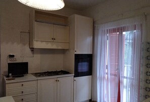 A kitchen with white cabinets, a stove, a black oven, and a television.