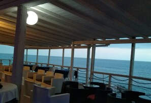 An outdoor seating area with tables and chairs, overlooking the sea.