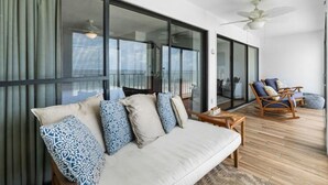 A spacious balcony with a sofa and chairs, large glass doors, and a ceiling fan. - Edgewater 41 (Gulf Shores)