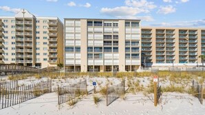 A beachfront hotel with multiple floors, a sandy beach in front, and a clear sky. - Edgewater 41 (Gulf Shores)