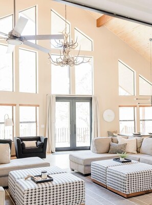 Un vaste salon doté d’un ventilateur de plafond, de grandes fenêtres et d’un lustre.
