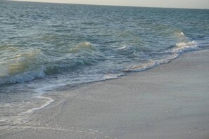 Enjoy a serene beach experience with gentle waves lapping onto the shore.
