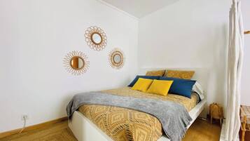 A bedroom with a bed, a bedside table, a lamp, and a window with curtains.
