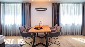 Een moderne eetruimte met een houten tafel, twee grijze gestoffeerde stoelen en een schaal fruit.