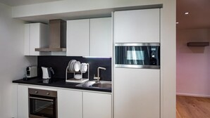 Een moderne keuken met witte kastjes, een roestvrijstalen oven, een koffiezetapparaat en een afwassysteem.