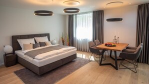 Een moderne hotelkamer met een groot bed, een houten eettafel en een zithoek.