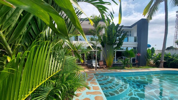 A pool area with clear water, surrounded by lush greenery and modern architecture. - Butterfly House (Malindi)
