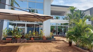 A modern building with large windows and a covered outdoor area with potted plants. - Butterfly House (Malindi)