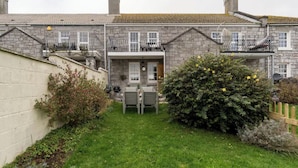 A two-story stone house with a small front garden, a wooden fence, and a satellite dish. - Beautiful Sea Front Cottage in the Ocean City (Plymouth)
