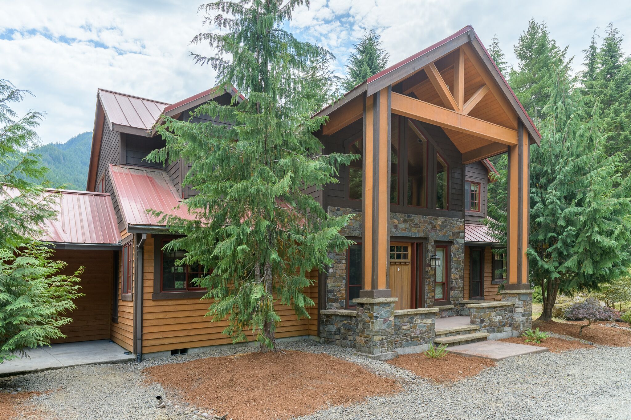 A log cabin with a stone foundation, large windows, and a metal roof.