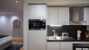 Una cocina moderna con horno empotrado, lavamanos y microondas.