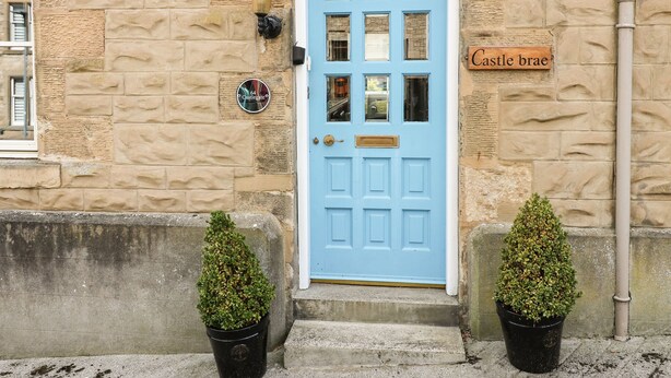 A blue door with a nameplate reading "Castle brae" and a street number sign "64 Castlegate." - Castlebrae (Jedburgh)