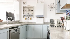 A modern kitchen with light blue cabinets, stainless steel appliances, and a wooden floor. - Castlebrae (Jedburgh)