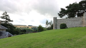 A grassy hill with a stone wall and a tower. - Castlebrae (Jedburgh)