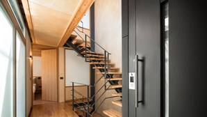 A modern interior with a wooden staircase, a black door, and a wooden floor. - Thallos the Boutique (Chania)