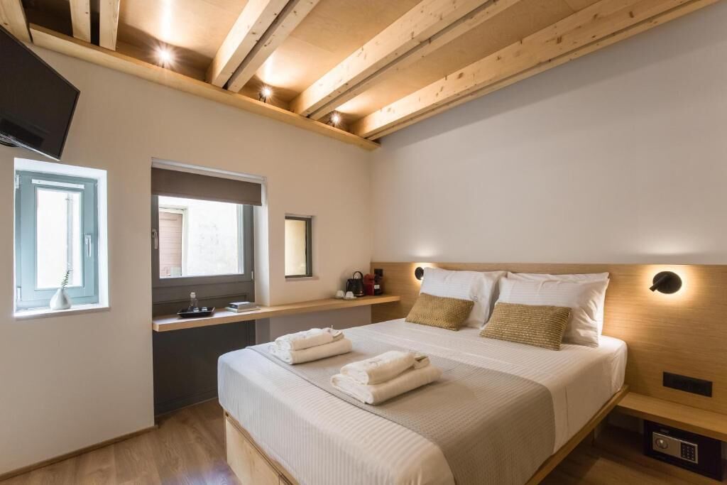 A bedroom with a bed, bedside tables, a mirror, and a window.