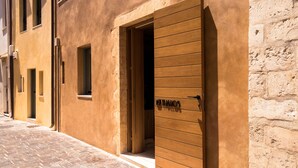 A building with a wooden door labeled "THAIOS" and a brick-paved street. - Thallos the Boutique (Chania)