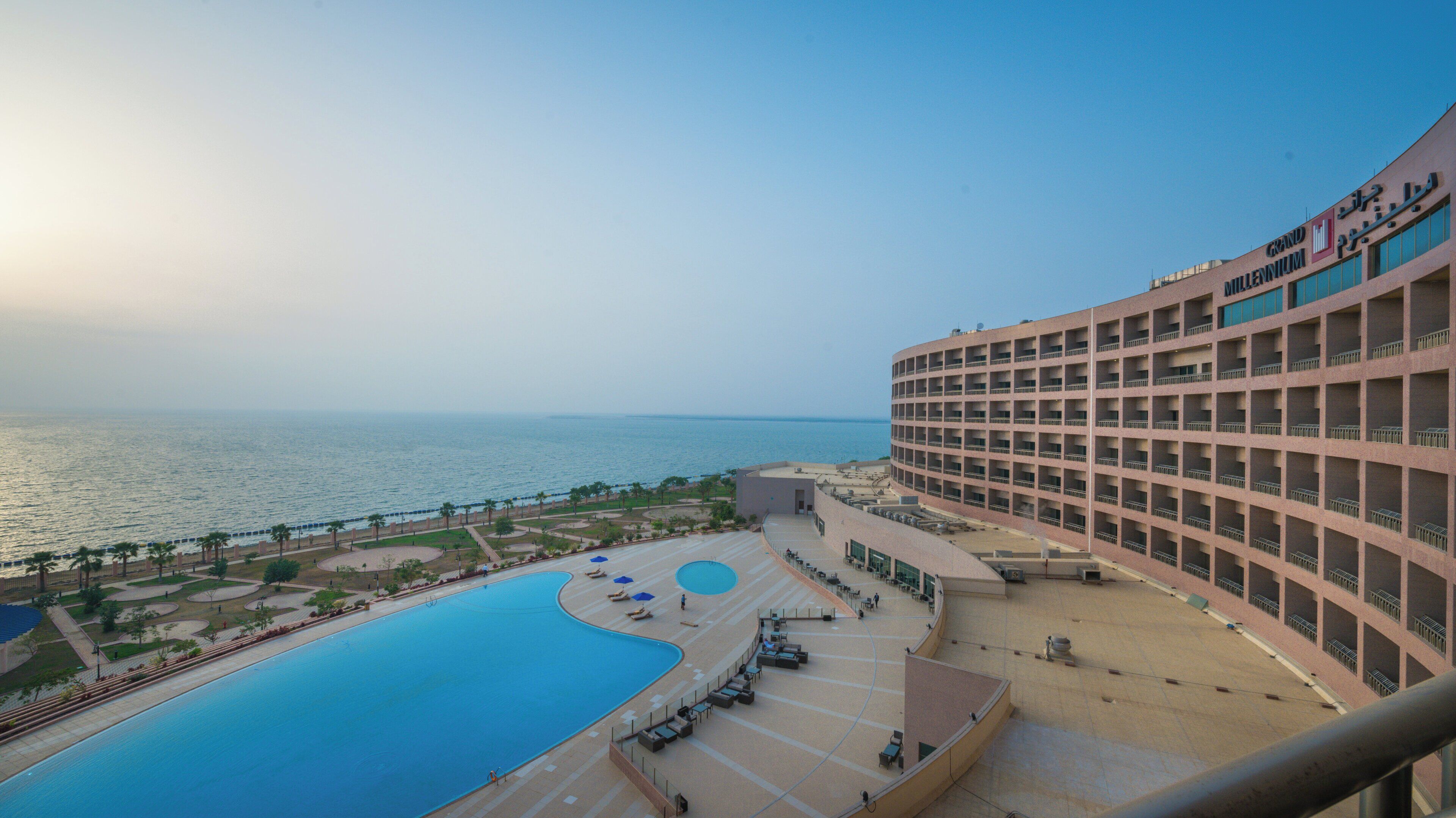 Un hotel con piscina, vistas al mar y un edificio grande con balcones.