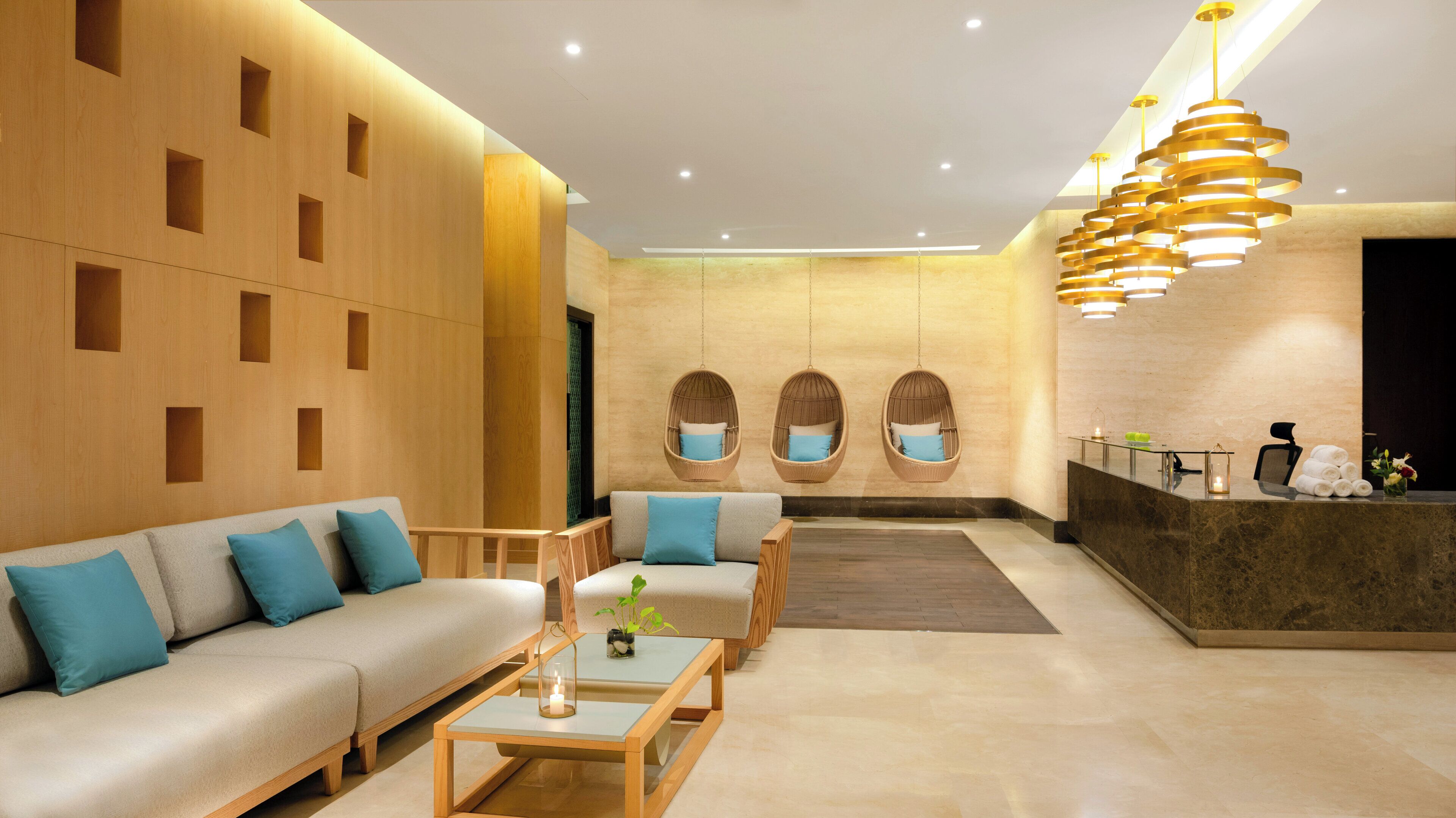 A modern lobby with a sofa, chairs, a reception desk, and hanging chairs.