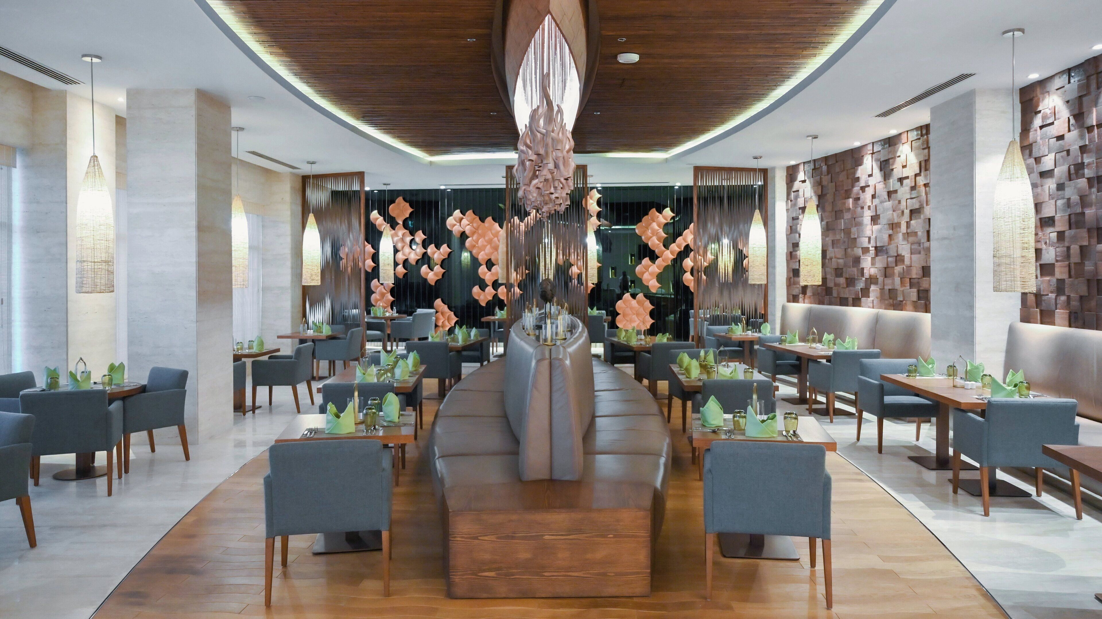 A modern restaurant with a central seating area, wooden ceiling, and contemporary decor.