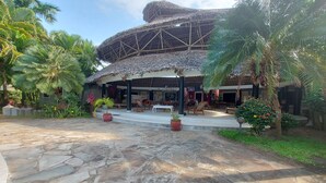 Un resort con una estructura de techo de paja, asientos al aire libre y abundante vegetación.