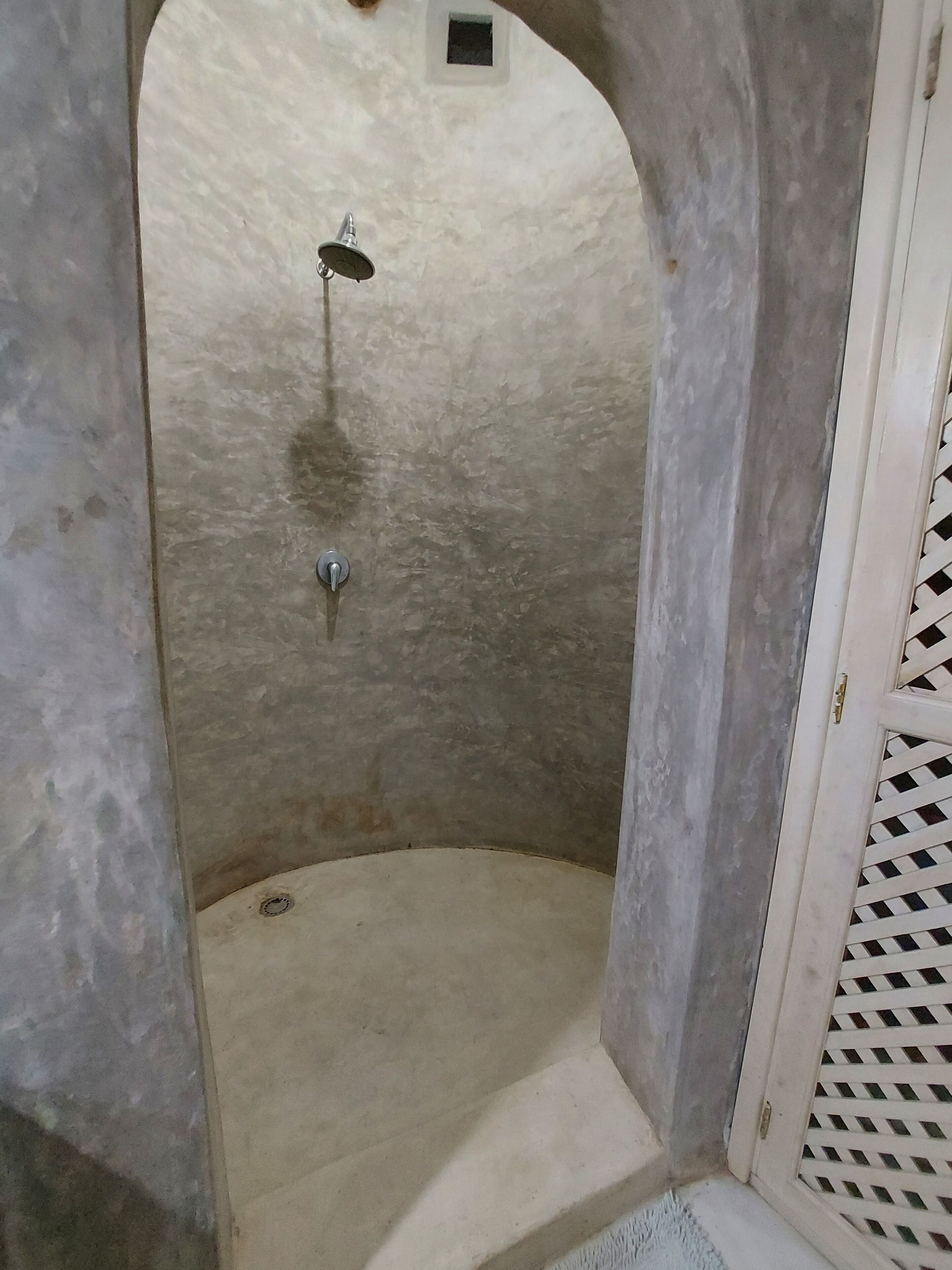 A small, enclosed shower area with a showerhead and a drain.