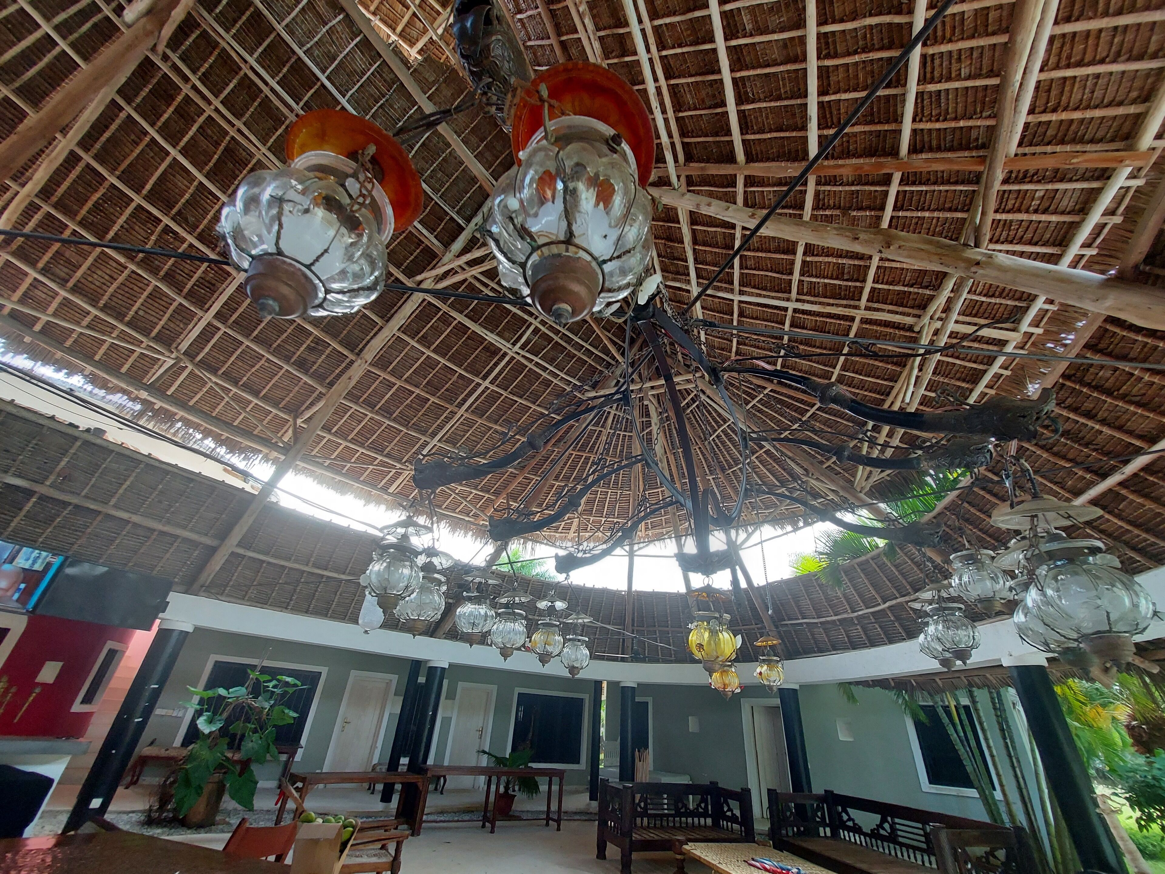 A spacious hall with a high thatched ceiling and multiple hanging light fixtures.