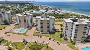 Ein hoch aufragender Wohnkomplex mit Innenhof, Swimmingpool und Blick auf den Strand.