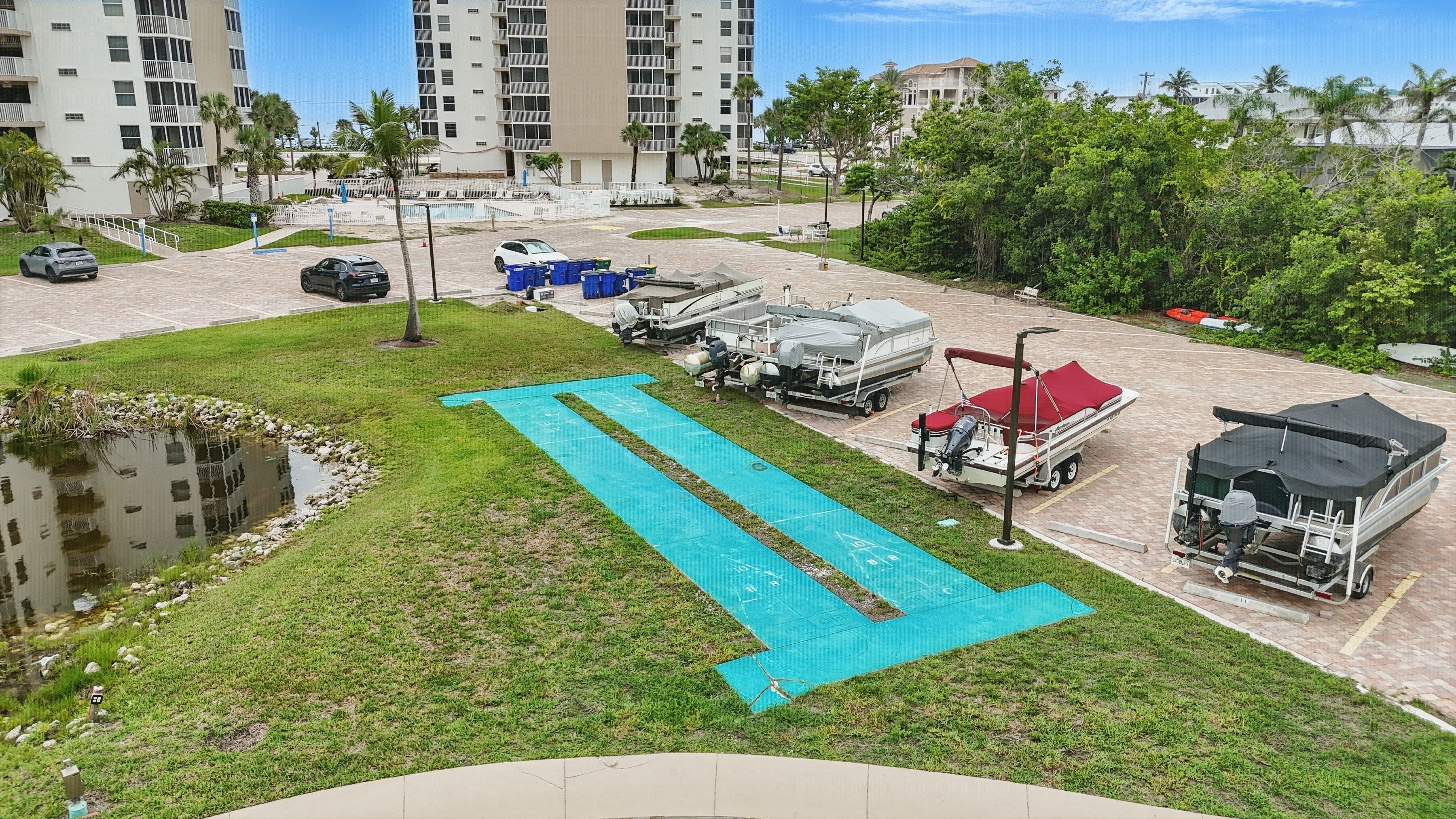 A parking area with boats, a swimming pool, and a building in the background.