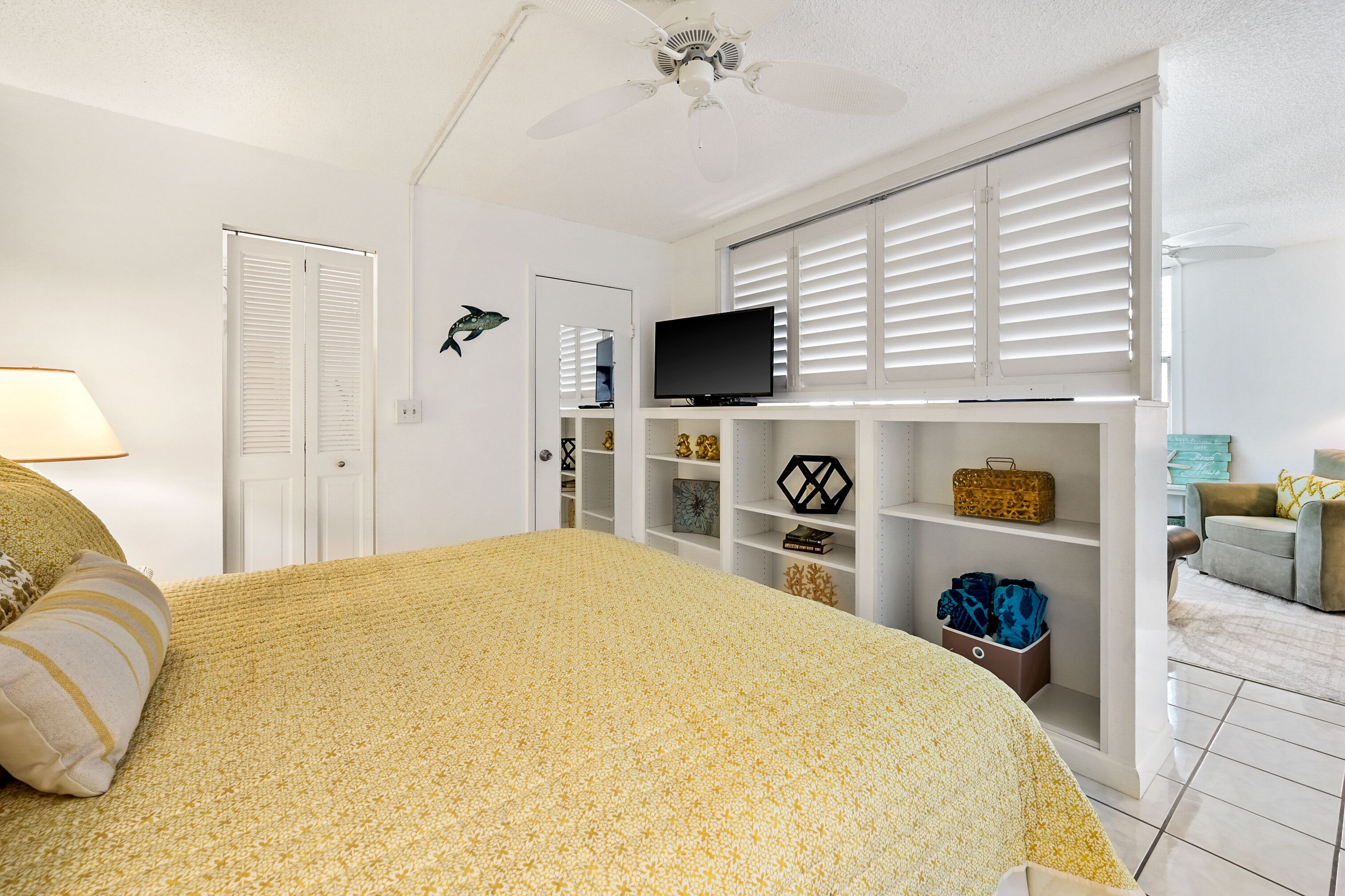 Un dormitorio con cama, televisión, armario y ventana con persianas.