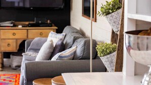 Un salon avec un canapé gris, une table d’appoint en bois et une table basse blanche.