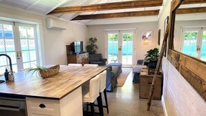 Une cuisine dotée d’un îlot central en bois, de meubles blancs et d’un coin repas avec des chaises bleues.