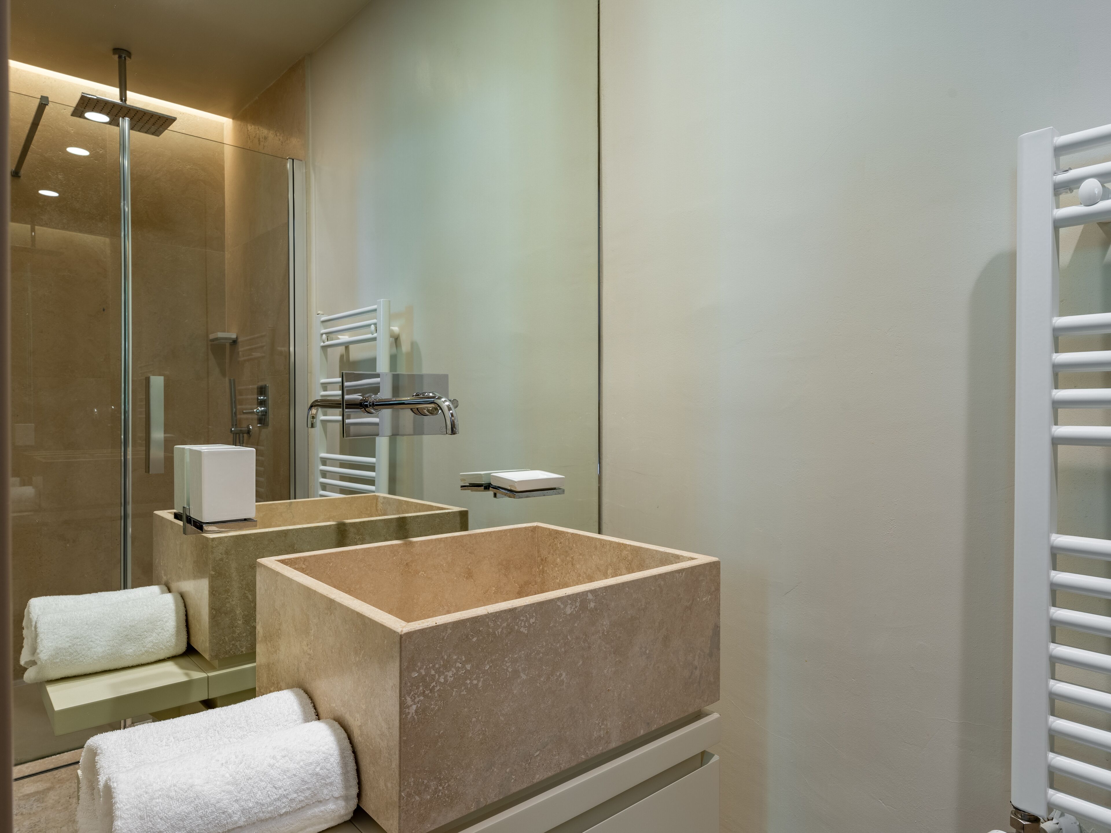 Ein modernes Badezimmer mit einer begehbaren Glasdusche, einem beigen Waschbecken und einem weißen Handtuchhalter.