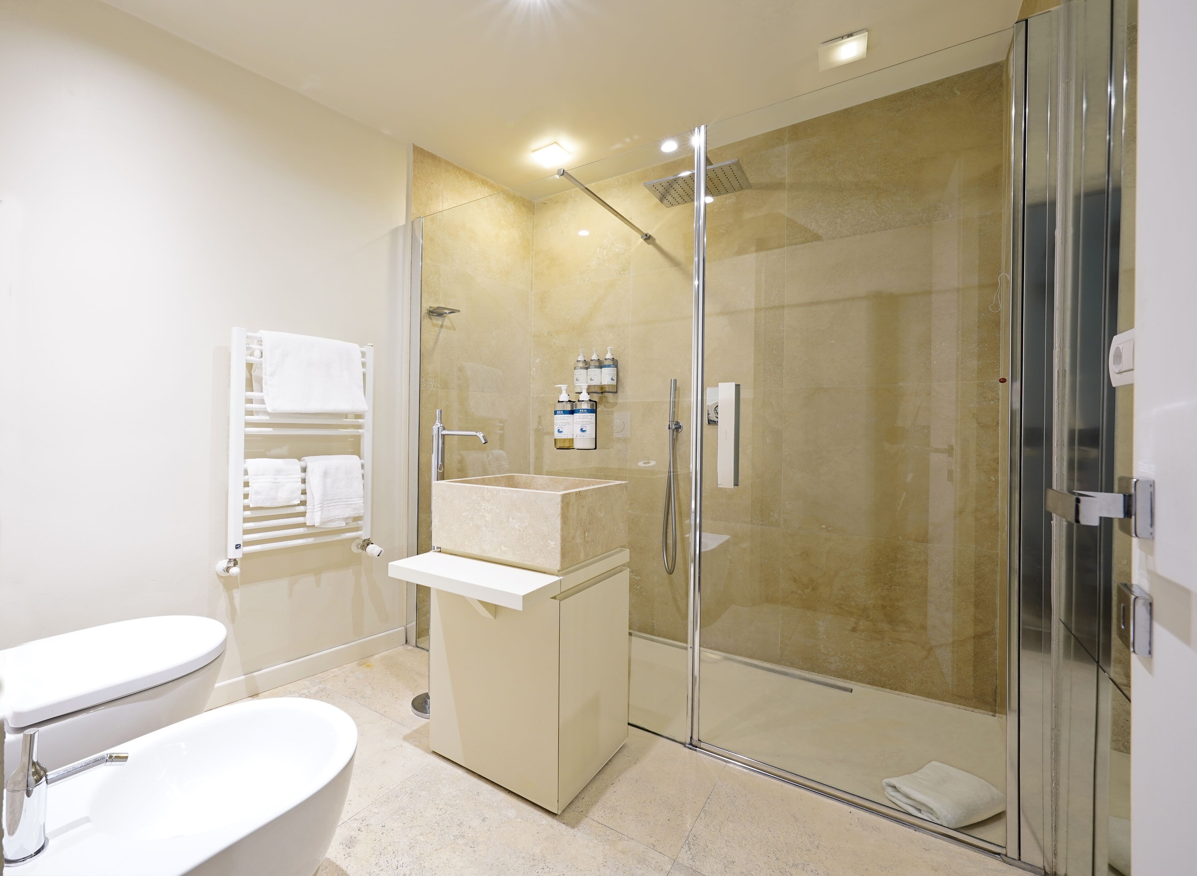 A modern bathroom with a glass-enclosed shower, a freestanding bathtub, and a vanity with a sink.