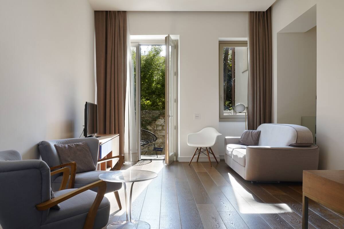 A modern living room with a sofa, armchair, and a small table.