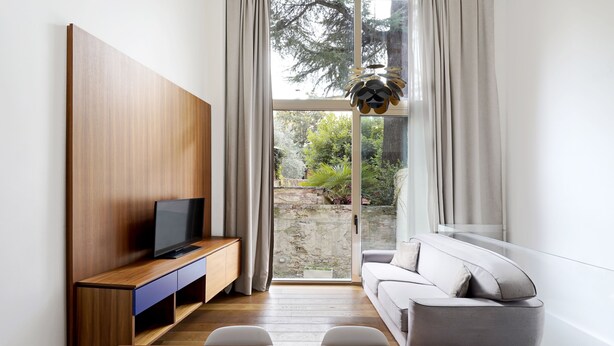 Una sala de estar moderna con un mueble de televisión de madera, un sofá gris y una mesa de comedor.