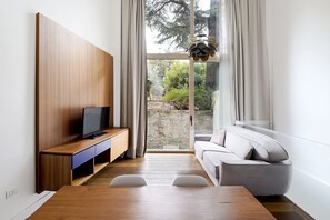 Una sala de estar moderna con un mueble de televisión de madera, un sofá gris y una mesa de comedor.