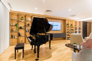 Una sala de estar moderna con un piano de cola, estantes de madera con diversos objetos, un televisor y una colección de vinos.