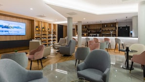 A modern lounge area with comfortable seating, a large TV screen, and a wine and spirits display. - Brit Hotel Paris Orly (Thiais)