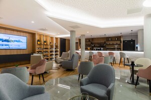 Un área de estar moderna con asientos cómodos, una gran pantalla de televisión y una vitrina de licores y vinos.