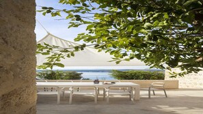 An outdoor seating area with white tables and chairs, a white canopy, and a view of the sea. - Villa Lapis by MyWaycation (Zavala)