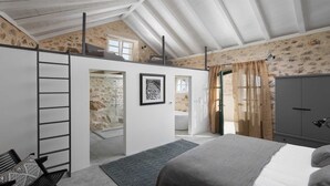 A bedroom with a loft bed, a ladder, a bathroom with a bathtub, and a wardrobe.