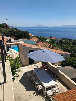 Une terrasse sur le toit avec une piscine, des espaces de détente en plein air et une vue sur la mer.